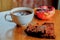 A piece of brownie with a Cup of coffee and a pomegranate on the wooden table