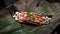 Piece of Burned Wagyu or Australia beef sushi with mayonnaise on bamboo leaf on black dish or plate at Japanese restaurant.