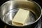 A piece of butter is melted in a steel saucepan