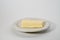 Piece of butter on white plate on white background