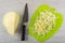 Piece of cabbage, knife, chopped cabbage on cutting board on wooden table. Top view