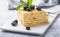Piece of cake Napoleon on white plate on concrete              background, close up view. Traditional millefeuille dessert with