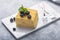 Piece of cake Napoleon on white plate on concrete              background, close up view. Traditional millefeuille dessert with