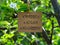 Piece of cardboard with the words Reduce Reuse Recycle on it hanging on a pear tree branch with blossoms and leaves using a wooden