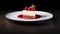 Piece of a cheesecake topped wit fresh raspberries on a white plate, side view over minimalist dark background with copy space
