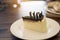 A piece of chocolate cake decorated with chocolate sheets in the white plate on the table