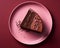 a piece of chocolate cake on a pink plate
