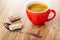 Piece of chocolate with dairy porous filling on spoon, cup with coffee on wooden table