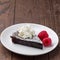Piece of chocolate sticky brownie cake, swedish dessert Kladdkaka, on the plate, garnished with icing sugar, whipping cream and