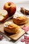 Piece of cinnamon apple pie on a wooden board with fresh apple in background, autumn food concept