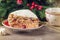 Piece of cranberry cake covered with white cream on plate on the background of the Christmas tree