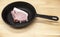 A piece of delicious fresh raw pork close-up on a cast iron skillet on the table rustic kitchen