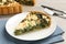 Piece of delicious homemade spinach quiche on table