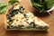 Piece of delicious homemade spinach quiche in wooden table, closeup