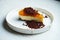 A piece of delicious New York cheesecake with orange pumpkin topping and topping on a white ceramic plate on a marble background