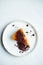 A piece of delicious New York cheesecake with orange pumpkin topping and topping on a white ceramic plate on a marble background