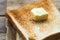 Piece of fresh butter on stacked toasted slice sandwich bread on gunny sack cloth on wooden table