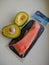 Piece of fresh salmon in a package and halves of avocado on a white table