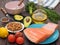 Piece of fresh salmon on a plate, avocado, almonds, sunflower oil and vegetables on a table