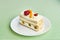 Piece of fruit yogurt cake with fresh strawberry, raspberry, peach, grapes and almonds on a white plate and pattern background.