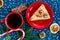 Piece of handmade apricot pie on red plate and red cup with tea or coffee with fir tree, pines, cinnamon on blue placemat