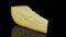 Piece of hard cheese rotating in a circle, black background, and space for text.