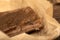 A piece of homemade bacon with pepper on white oiled paper, close-up, selective focus