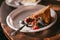 A piece of homemade blueberry and raspberry pie lies on a plastic white plate with silver spoon against the backdrop of