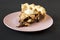 A piece of homemade Chocolate Walnut Derby Pie on a pink plate over black background, low angle view. Close-up