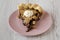 A piece of homemade Chocolate Walnut Derby Pie on a pink plate on a white wooden background, side view. Close-up