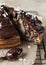 Piece of homemade marble cake with chocolate glaze and nuts on wooden plate. Chocolate vanilla zebra pie