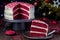 Piece of homemade red velvet cake with cream cheese frosting on a metal plate, low key photo with boke lights and christmas