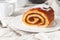 A piece of homemade sponge cake with apple jam. On a white plate. In the background is a white teapot and a mug. Close-up