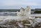 A piece of ice resembling a fist on the shore of a lake with waves