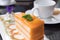 Piece of layer orange cake on the plate at coffee shop in the morning. people eat cake and drink coffee for breakfast, lunch or