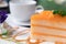 Piece of layer orange cake on the plate at coffee shop in the morning. people eat cake and drink coffee for breakfast, lunch or