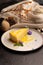 A piece of lemon cheesecake garnished with mint flowers and leaves and lemon sauce.