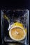 Piece of lemon in a glass vessel. Black background
