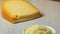 Piece of mature cheese  and a bowl with grated cheese in front close up