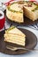 Piece of Mocha coffee layered cake with butter cream, pistachio, mug in red knit shirt, close-up white background.