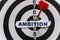 A piece of paper with the text is nailed to the target with a dart - AMBITION