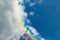 Piece of picturesque multicolored rainbow on the romantic sky. Clear afternoon day with white clouds