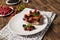 Piece of pie with blueberries, rasberry and mint for dessert on a white plate, napkin on a wooden boards background.