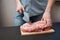 Piece of pork neck cutout on woodwn table. Man cutting meat