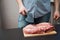 Piece of pork neck cutout on woodwn table. Man cutting meat