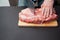 Piece of pork neck cutout on woodwn table. Man cutting meat