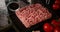 A piece of raw minced meat on cutting board with tomatoes.