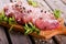 Piece of raw pork meat with salt and pepper on wooden board with herbs