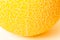 A piece of round yellow melon on a white surface. Texture.