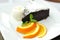 A piece of Sachertorte with ball of vanilla ice cream, three orange slices and mint spring